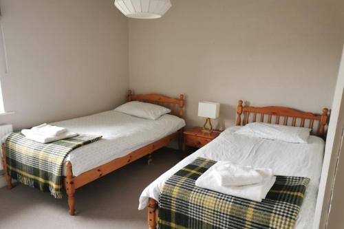 two twin beds in a bedroom with a lamp at Detached cottage overlooking lake in Connemara in Ballyconneely