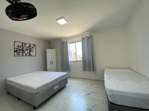 1 dormitorio con 2 camas y ventana en Apartamento 1 quadra do mar en Pontal do Paraná