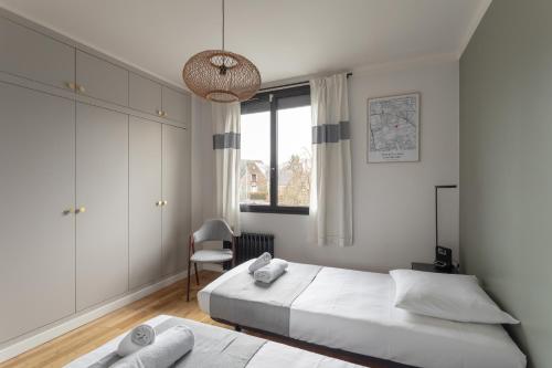 - une chambre blanche avec 2 lits et une chaise dans l'établissement La Cocotte - Maison pour 6 quartier Sainte-Thérèse, à Rennes