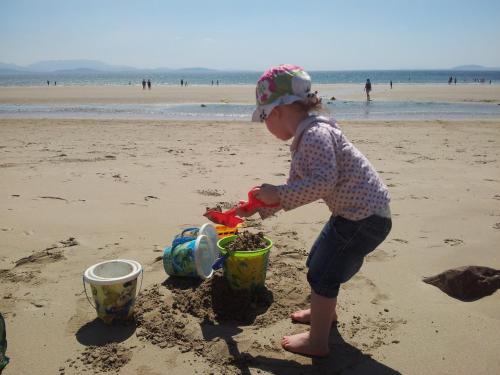 a little girl playing in the sand on the beach at Stone fronted detached cottage just over 2 miles from Mulranny village in Mulranny