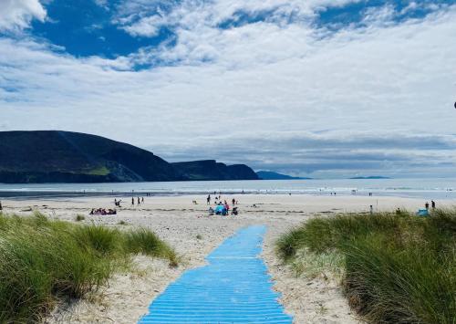 a beach with blue beach towels on the sand at Stone fronted detached cottage just over 2 miles from Mulranny village in Mulranny