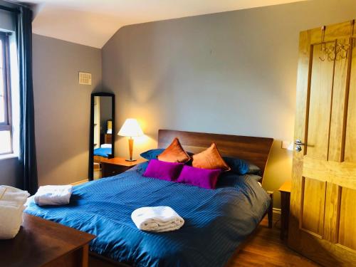 a bedroom with a blue bed with purple pillows at 3 bedroomed home just 15 mins walk from Kenmare town in Kenmare