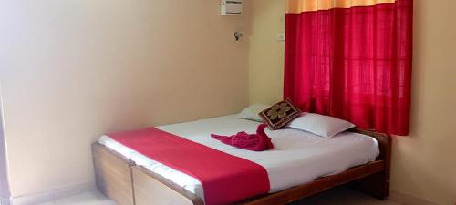 a bedroom with a bed with a red curtain at Ahobila Delux Homes in Tiruchchirāppalli