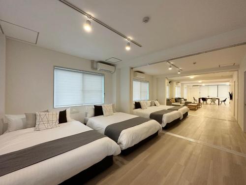 ein Hotelzimmer mit 3 Betten und einem Tisch in der Unterkunft bHOTEL Kaniwasou 201 2BR Apt, Near Itsukushima Shrine, For 12 Ppl in Hatsukaichi