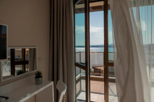 a room with a balcony with a view of the ocean at St. Panteleimon Beach Hotel in Nesebar