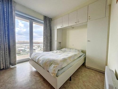 ein Schlafzimmer mit einem großen Bett und einem großen Fenster in der Unterkunft Appartement front de mer in Bray-Dunes