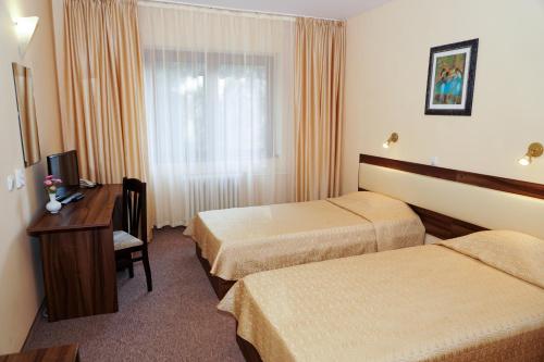 Pokój hotelowy z 2 łóżkami, biurkiem i oknem w obiekcie Hotel Bor w Borowcu
