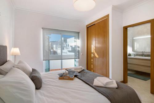 a bedroom with a large white bed and a window at Casa Mar-a-vila in Olhão