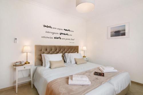 a bedroom with a large white bed with a writing on the wall at Casa Mar-a-vila in Olhão