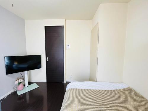 a bedroom with a bed and a flat screen tv at 20 mins Direct to Ueno 21 mins to Ikebukuro Max for 3 peole Nishikawaguchi302 in Kawaguchi