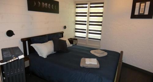 1 dormitorio con cama con sábanas azules y ventana en Domaine Moulin Blanc - Gîte Triskel, en Meslan
