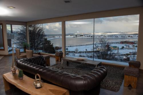 a living room with a leather couch and a large window at Hotel Las Lengas in Ushuaia