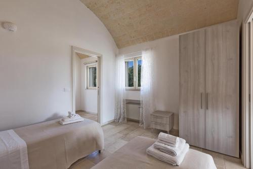 a white bedroom with two beds and a window at Villa Angi by Perle di Puglia in San Vito dei Normanni