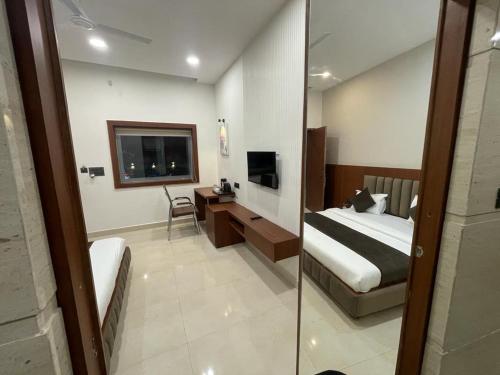a bedroom with a bed and a tv and a desk at The Kedar Resort in Mathura