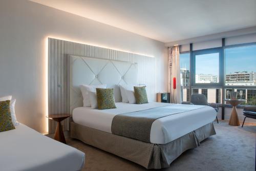 a hotel room with a large bed and a large window at Le Parisis - Paris Tour Eiffel in Paris