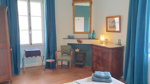 Habitación con cortinas azules, tocador y espejo. en Au bord de la Dronne, en Bonnes