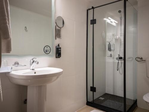 La salle de bains est pourvue d'un lavabo et d'une douche. dans l'établissement ibis Styles Pitesti Arges, à Piteşti