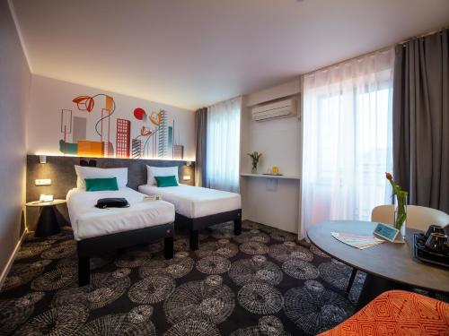 a hotel room with two beds and a table at ibis Styles Pitesti Arges in Piteşti