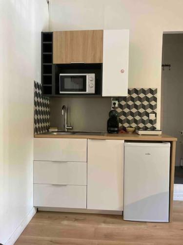 une cuisine avec des armoires blanches et un micro-ondes dans l'établissement Studio hypercentre Quai de Seine, à Rouen