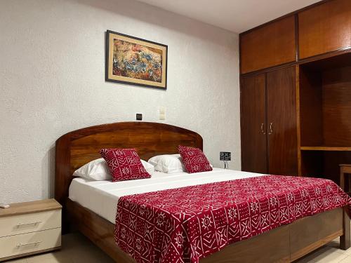 a bedroom with a large bed with a red blanket at BAMBOO LODGE - la Criquet 'Event' in Lomé