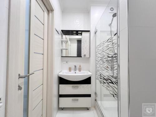a white bathroom with a sink and a shower at RentHouse Apartments Deep Purple in Chişinău