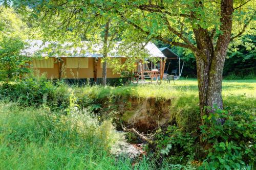 una casa en medio de un campo con un árbol en Camping Drei Spatzen, en Utscheid