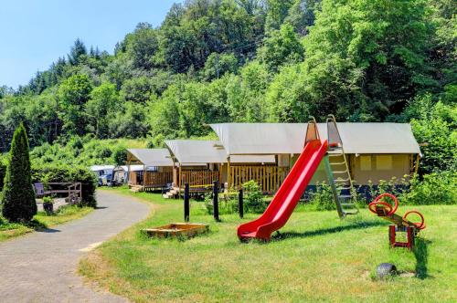un parque infantil con un tobogán rojo en el césped en Camping Drei Spatzen en Utscheid
