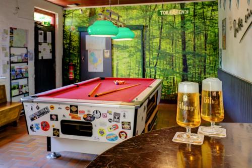 due bicchieri di birra su un tavolo accanto a un tavolo da biliardo di Camping Drei Spatzen a Utscheid