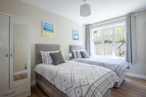2 Betten in einem Schlafzimmer mit Fenster in der Unterkunft Family Beach House 200m to Sea 10min to Centre in Pembrokeshire