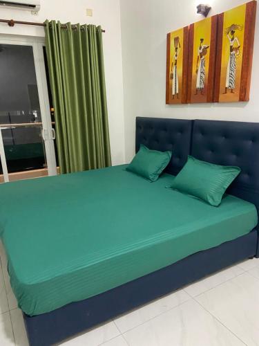 a blue bed with green pillows in a room at Sea view A in Mount Lavinia