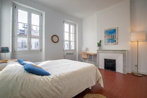 une chambre blanche avec un lit et une cheminée dans l'établissement Appartement lumineux et central Vieux-Port, Opéra, à Marseille