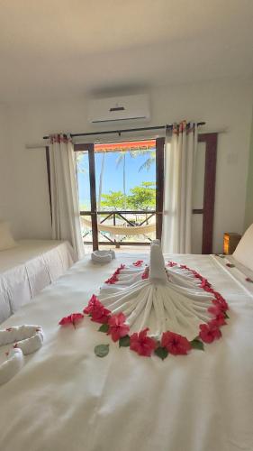 a white bed with a flower arrangement on it at Igarakuê Flat in Japaratinga