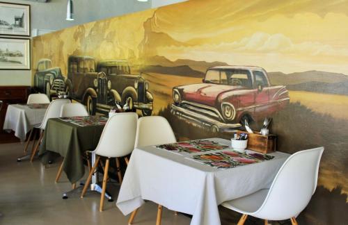 a dining room with tables and a mural of cars at Barrydale Karoo - BOUTIQUE HOTEL in Barrydale
