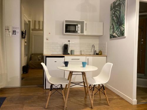 une petite cuisine avec une table et des chaises blanches dans l'établissement Studio N 2 cosy hypercentre, rue Saint Nicolas, à Rouen