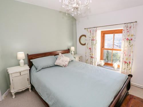 a bedroom with a blue bed with a window at Hillside Holiday Cottage in Treorky