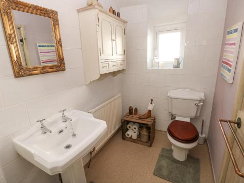 ein Badezimmer mit einem Waschbecken, einem WC und einem Spiegel in der Unterkunft Hillside Holiday Cottage in Treorky