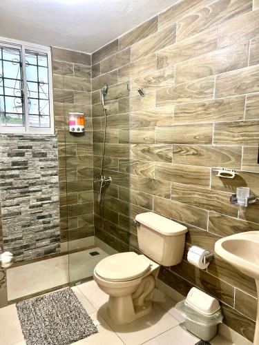 a bathroom with a toilet and a shower and a sink at Hotel Maria Bonita Higüey in Higuey