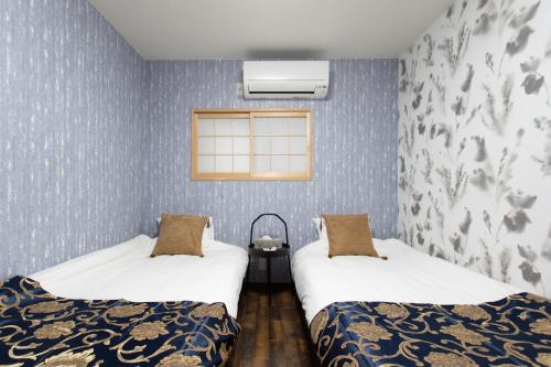 two beds in a room with blue wallpaper at 静響の宿 Silent Echo Inn in Osaka