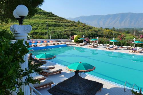a large swimming pool with chairs and umbrellas at Edva Resort in Vlorë