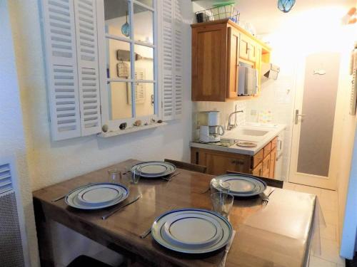 eine Küche mit einem Holztisch mit Tellern darauf in der Unterkunft La Palmyre - CHARMANTE VILLA MITOYENNE avec TERRASSE CLOSE in Les Mathes