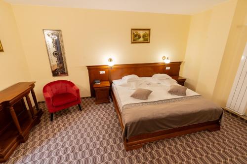 a bedroom with a bed and a desk and a red chair at Hotel Dorna in Vatra Dornei