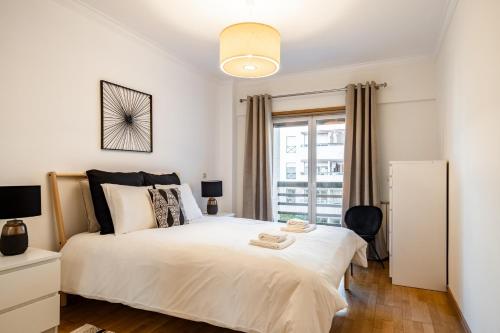 a bedroom with a large white bed and a window at Akicity Santa Apolónia Green in Lisbon