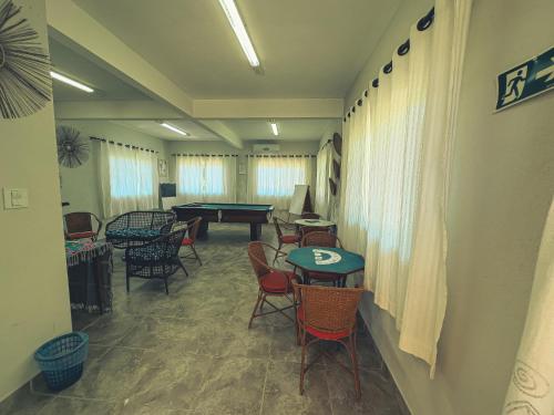a room with tables and chairs and a pool table at Igarakuê Flat in Japaratinga