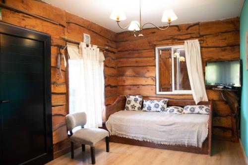 a bedroom in a log cabin with a bed and a chair at Cabañas El Viejo Sauce in Tandil