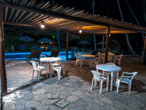a group of tables and chairs under a pavilion at Igarakuê Flat in Japaratinga