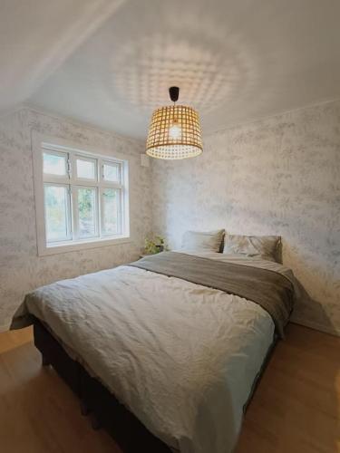 a bedroom with a large bed and a chandelier at Bellahuset - Charming House in Ulsteinvik in Ulsteinvik