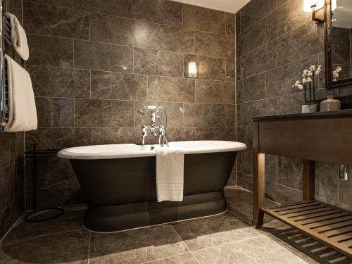 a bathroom with a bath tub and a sink at Dakota Glasgow in Glasgow