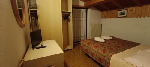 a bedroom with a bed and a desk with a television at Pizzeria Marmolada Camere in Sottoguda