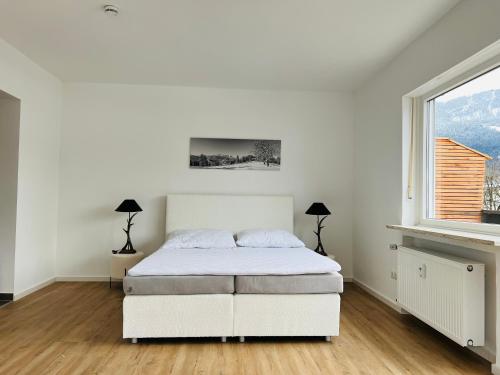 a white bedroom with a bed and a window at The View Apartment in Garmisch-Partenkirchen