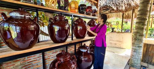 a woman standing in front of a shelf of vases at Song Ngư Riverside Homestay in Can Tho